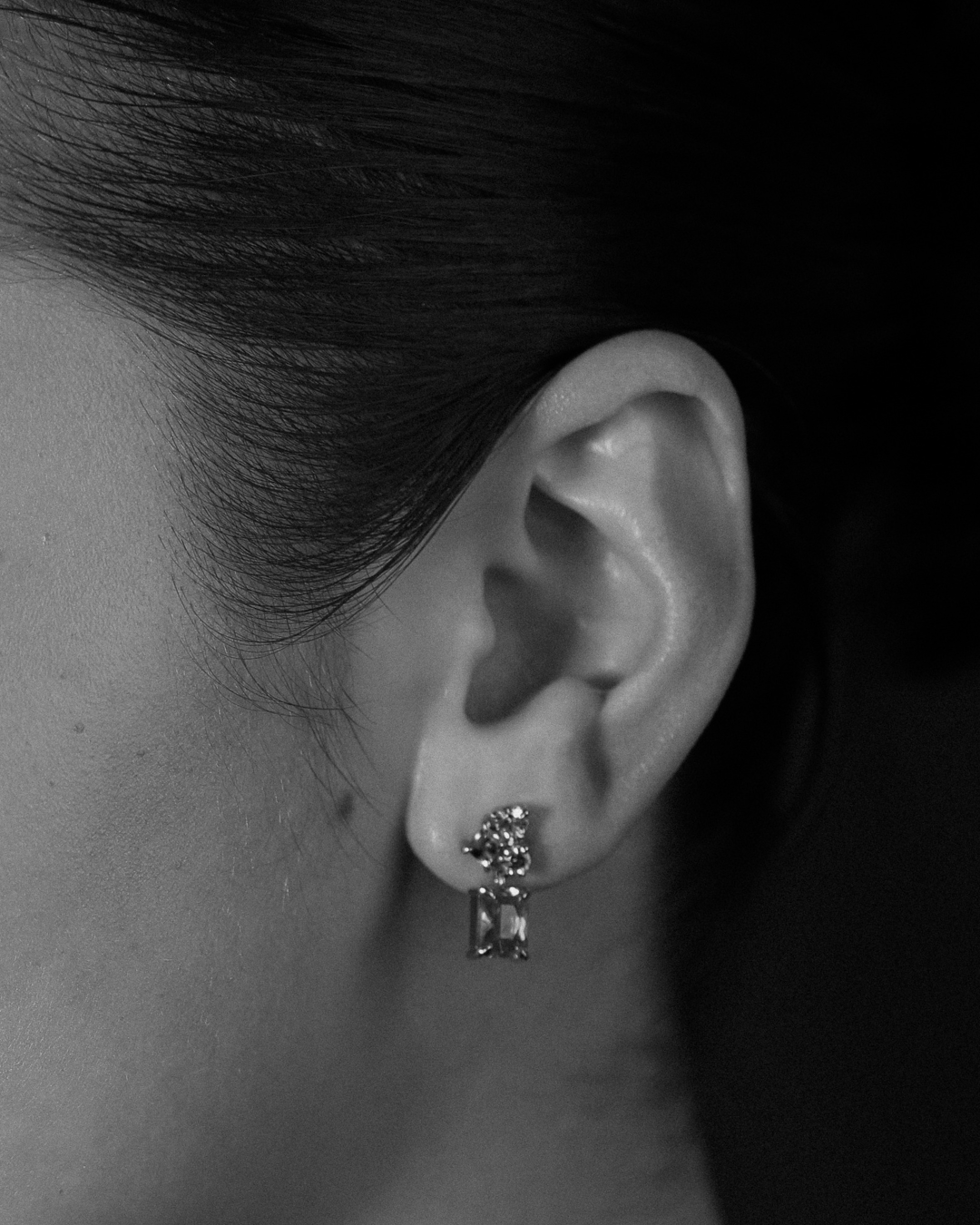 close-up of an ear wearing a gemstone drop earring