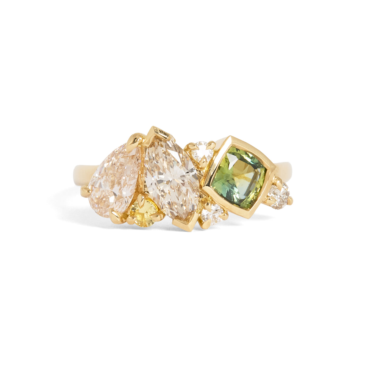 A gold ring featuring a cluster of diamonds, including a large pear-cut diamond, a marquise-cut diamond, a cushion-cut green gemstone, and small accent diamonds, set on a plain white background.