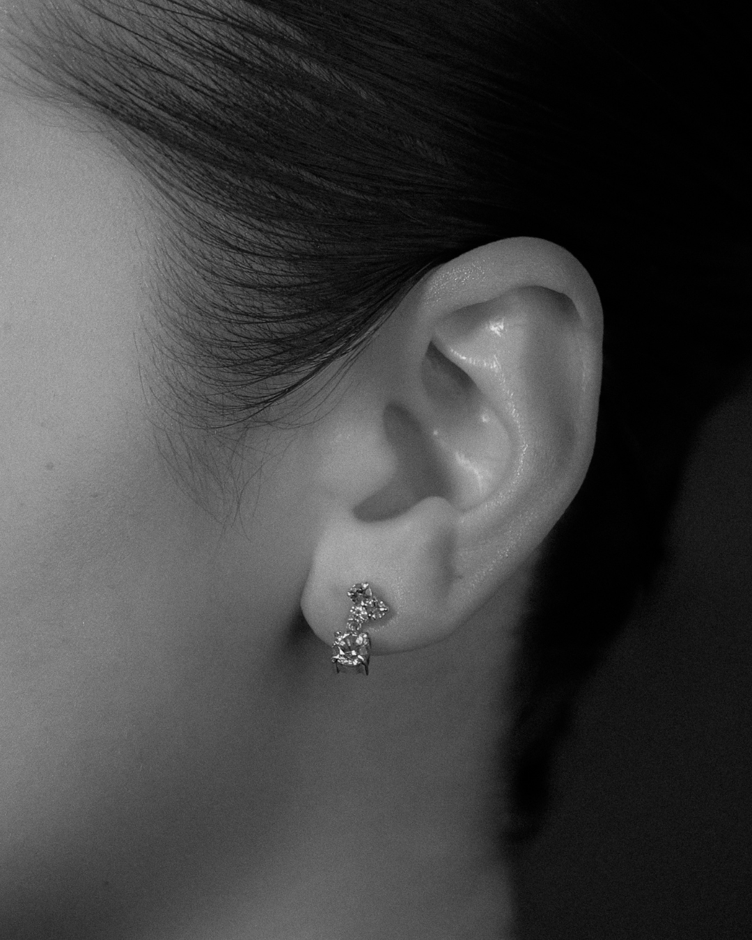 Close-up of an ear wearing a gemstone earring with a dark background
