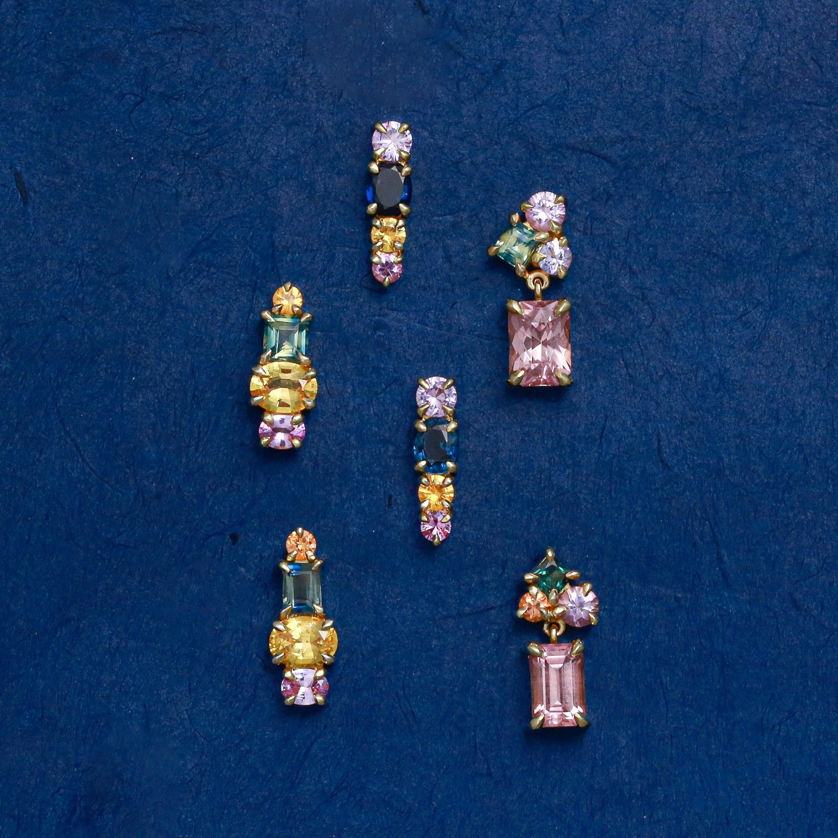 colourful gemstone stud earrings on blue background