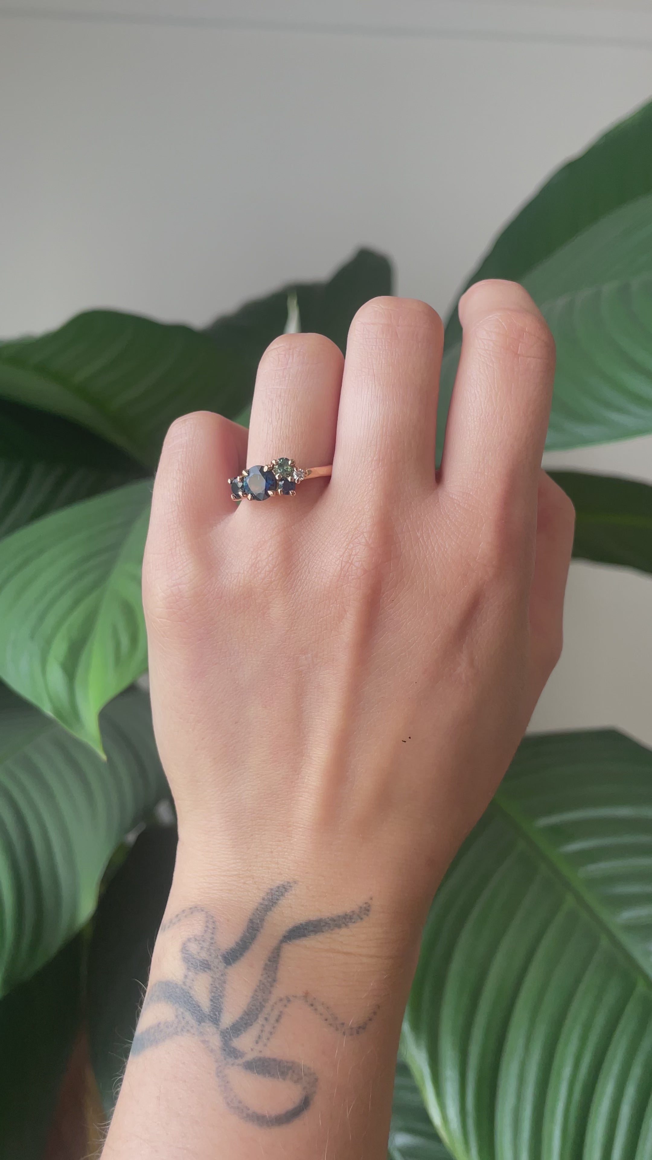 green sapphire cluster ring shimmering in light worn on finger