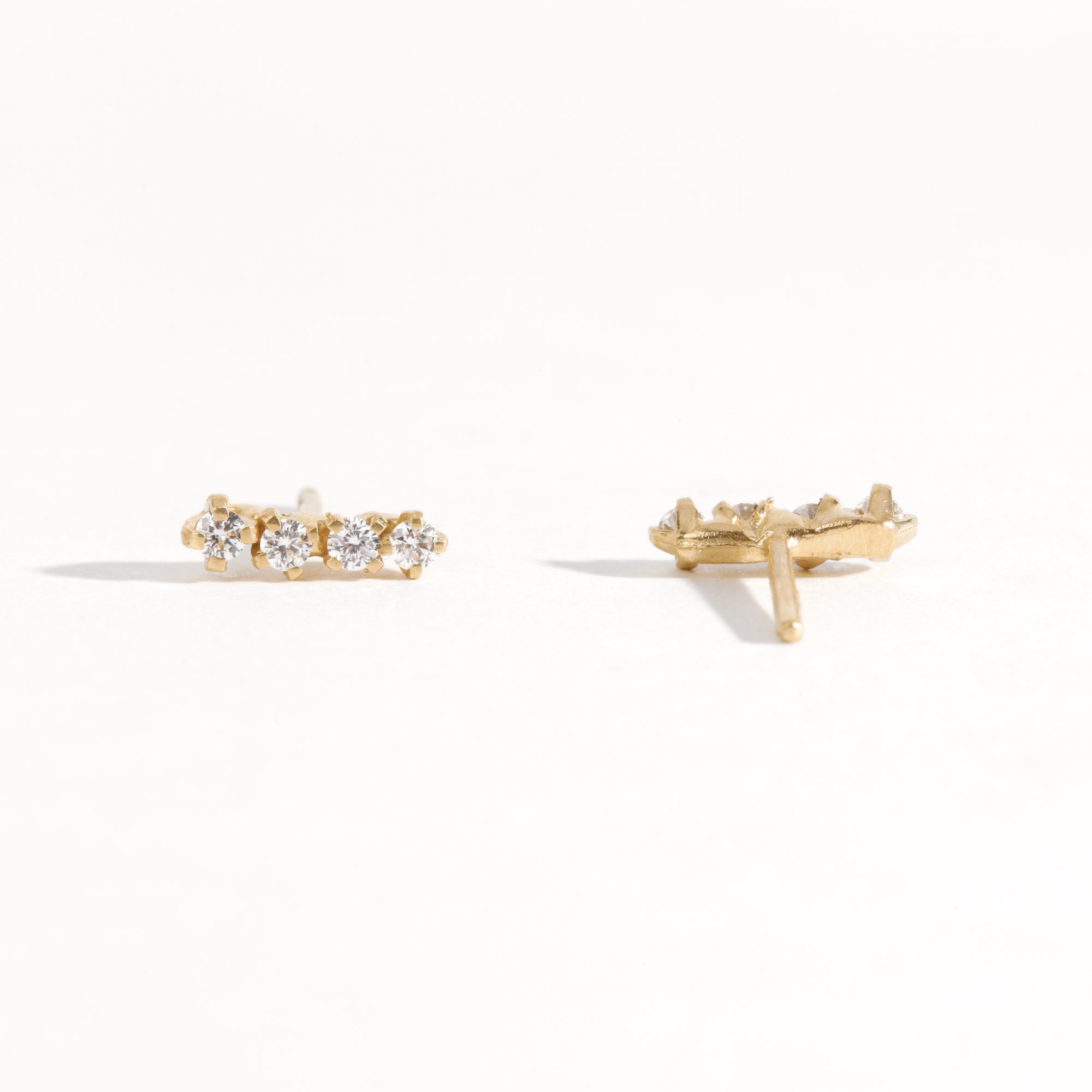 A pair of earring studs crafted with 9ct recycled refined yellow gold with a row of four diamonds by Black Finch Jewellery