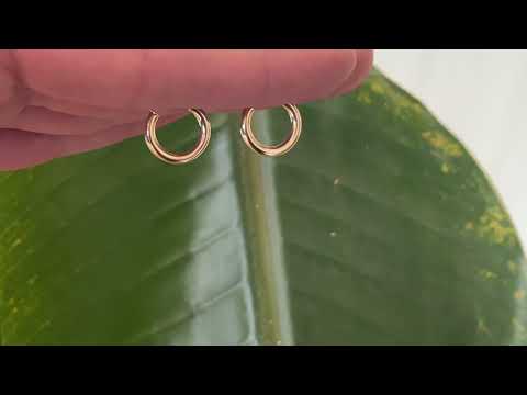 Classic 9 carat yellow gold hoops, displayed on the hand, gently catching the sunlight.