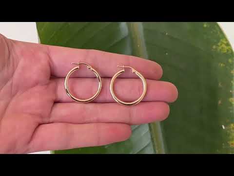 Classic 9 carat gold hoop earrings, displayed on the hand, catching the sun.