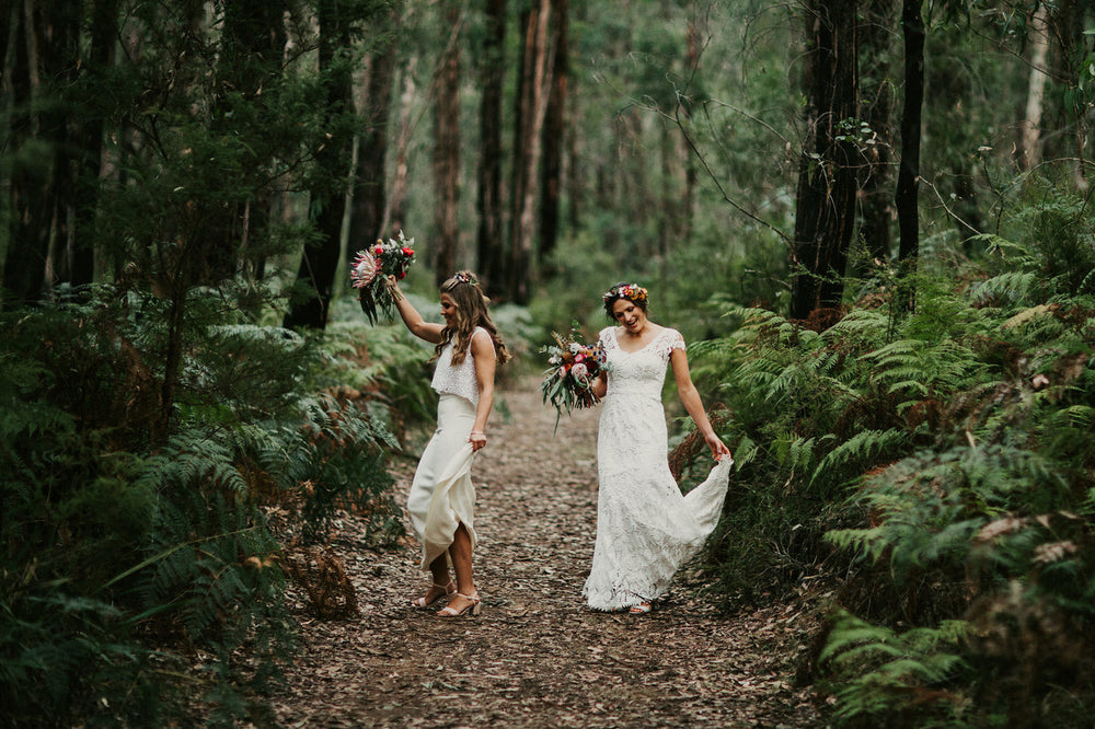 Two brides walking in a forrest on their wedding day