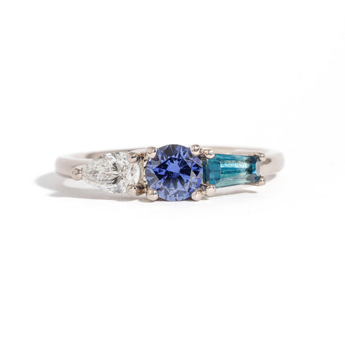 Three Stone Ring with Centre Blue Sapphire, Round White Diamond and Tapered Blue Baguette Sapphire Side Stones in 18 Carat White Gold
