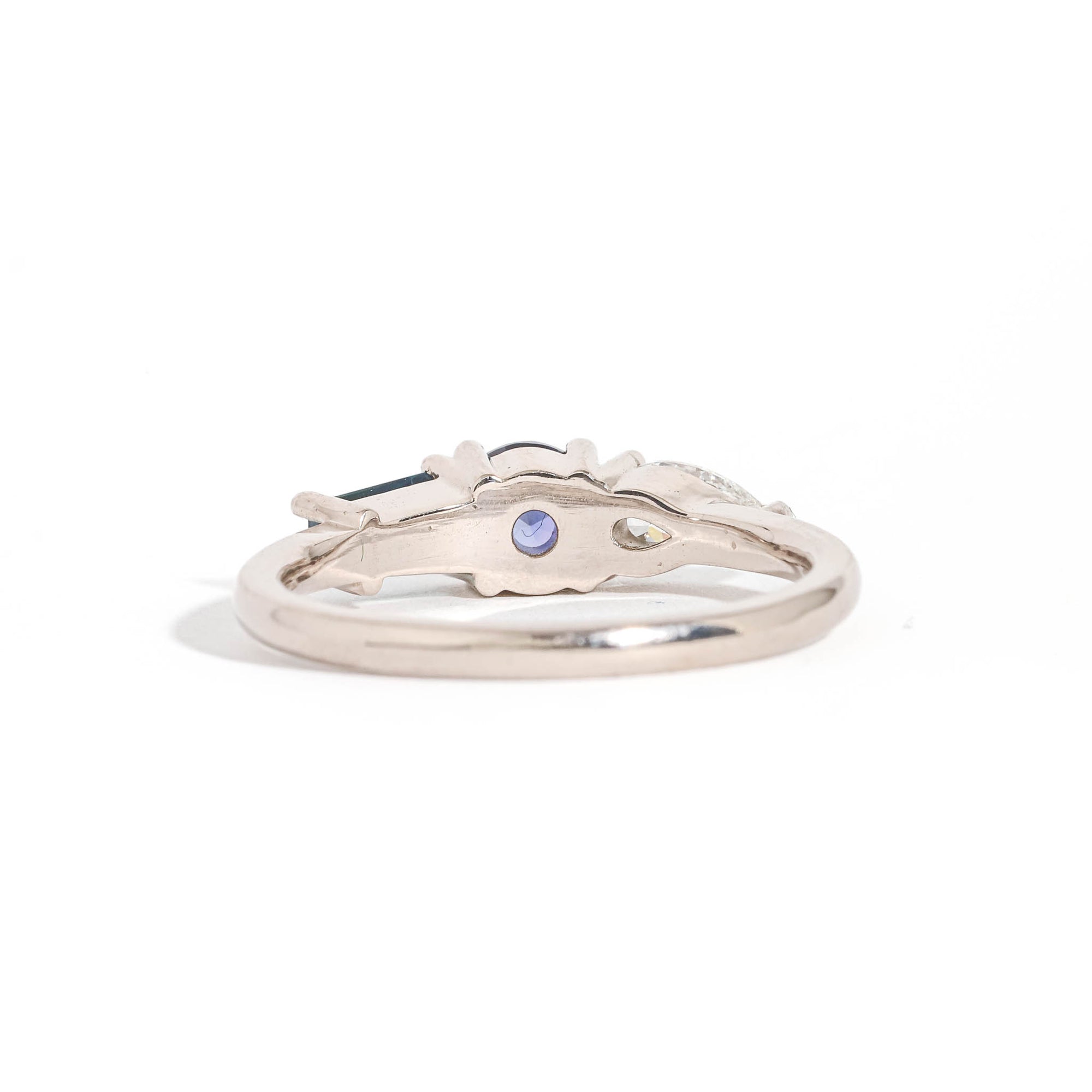 Three Stone Ring with Centre Blue Sapphire, Round White Diamond and Tapered Blue Baguette Sapphire Side Stones in 18 Carat White Gold