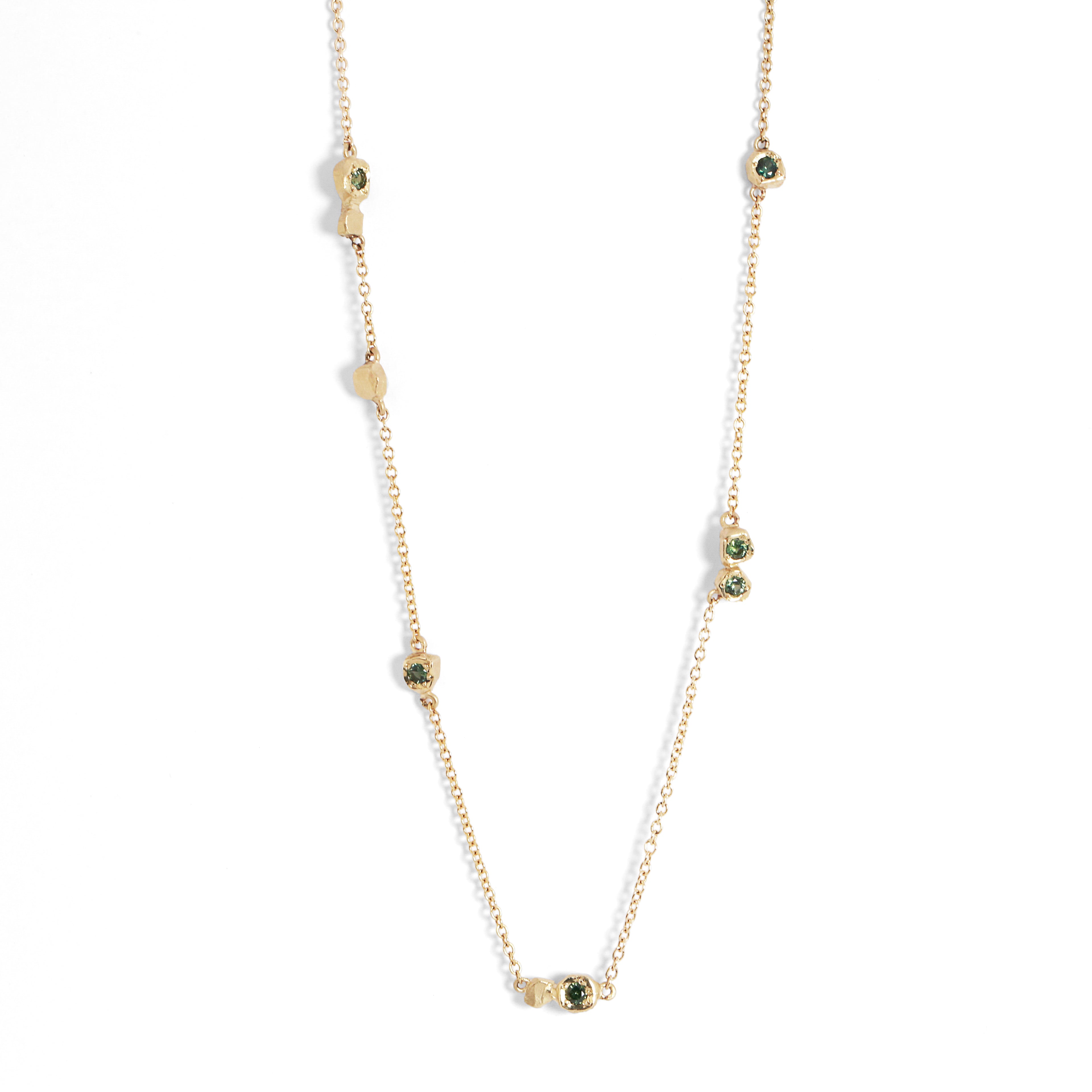 Gold necklace with green gemstones on a white background