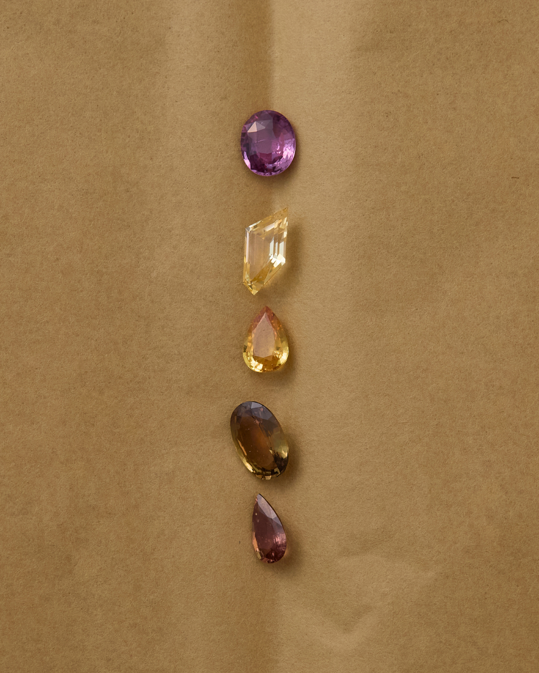 Set of loose warm toned sapphires on a brown paper background