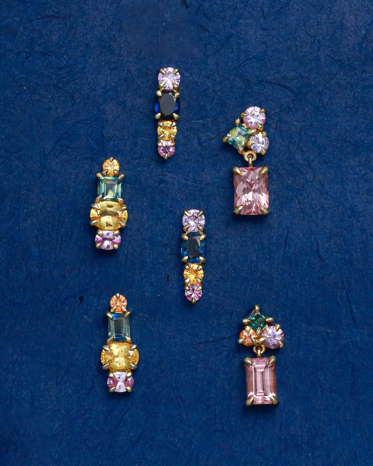 colourful gemstone stud earrings on blue background