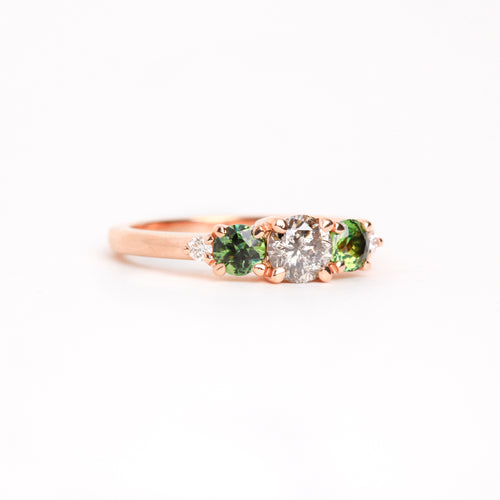  Featured in 18 carat rose gold, a five stone ring with one central round salt and pepper diamond, two round ethically sourced green Australian sapphires, and two round white diamonds. 