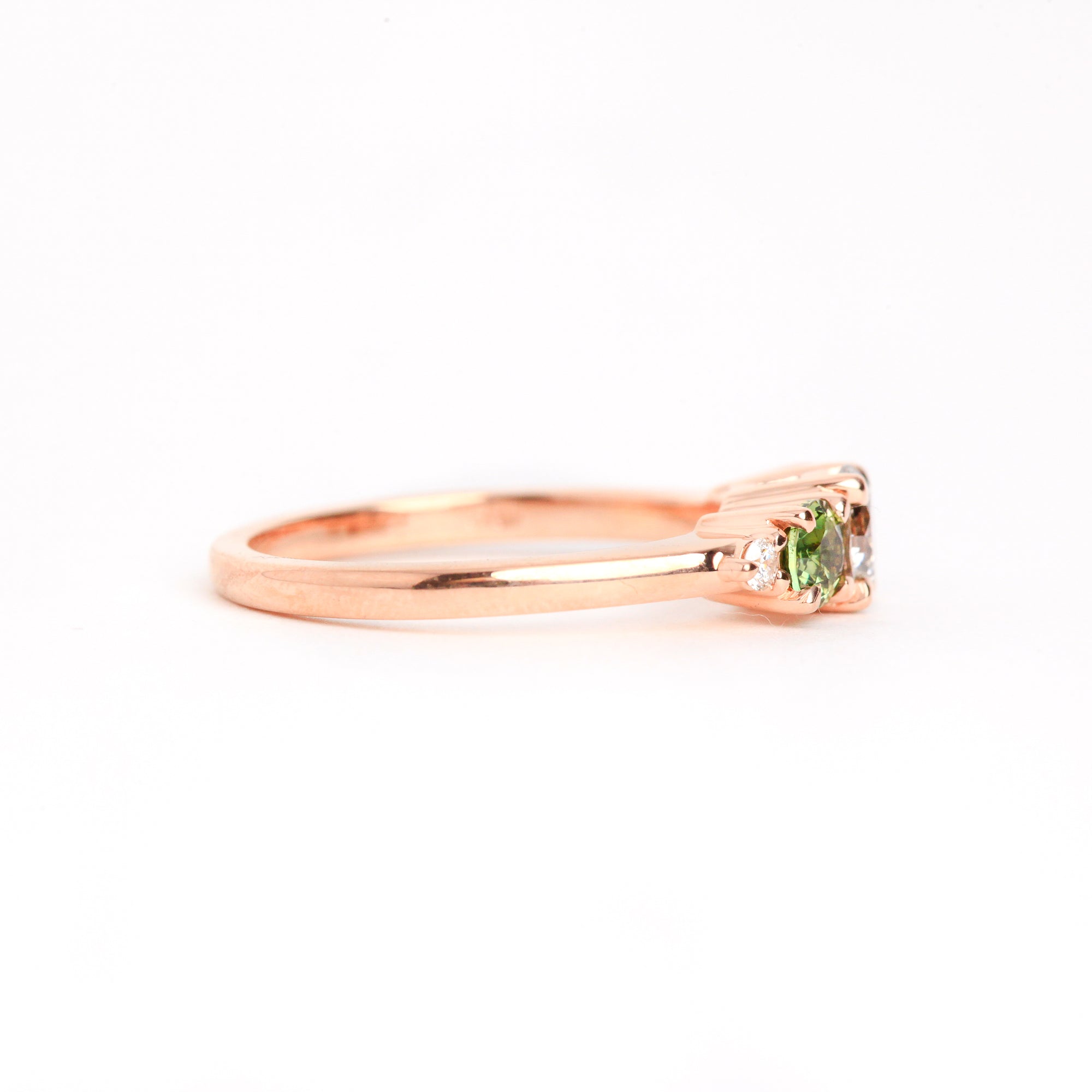  Featured in 18 carat rose gold, a five stone ring with one central round salt and pepper diamond, two round ethically sourced green Australian sapphires, and two round white diamonds. 