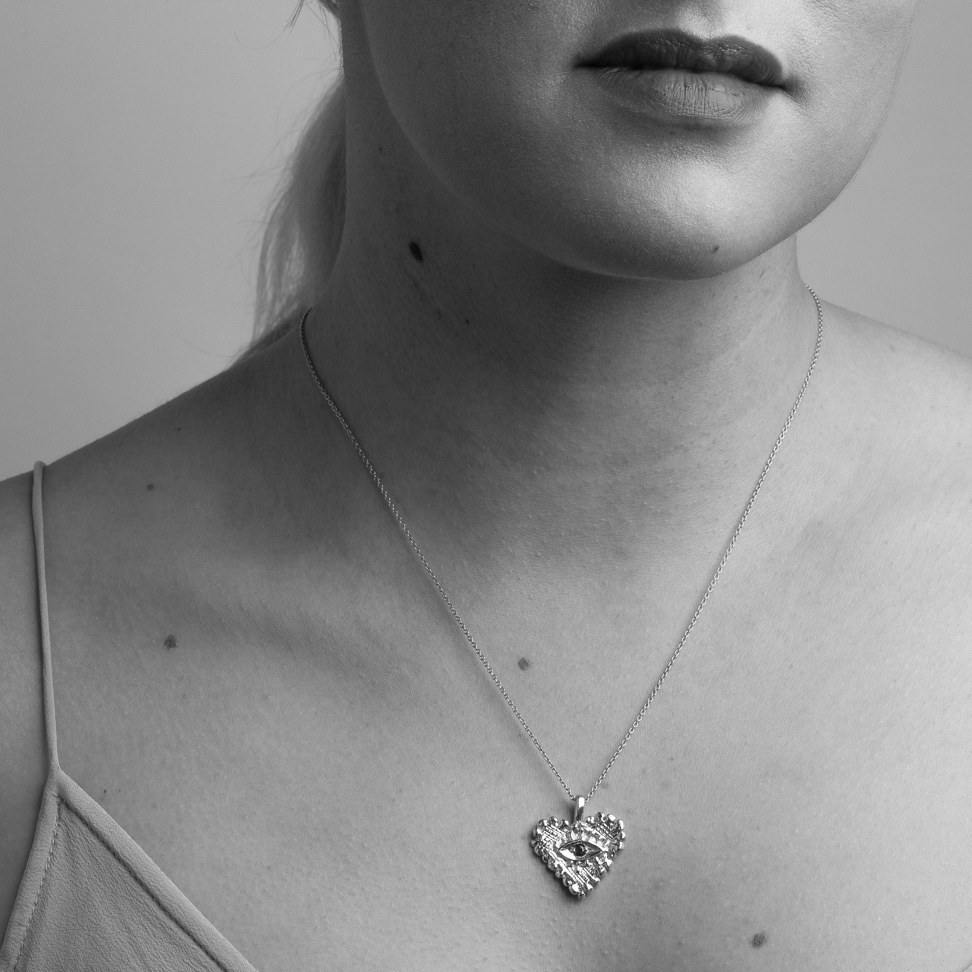 Handmade 9 carat yellow gold heart pendant set with a ruby in centre of eye detail on 9 carat yellow gold chain worn on the neck.