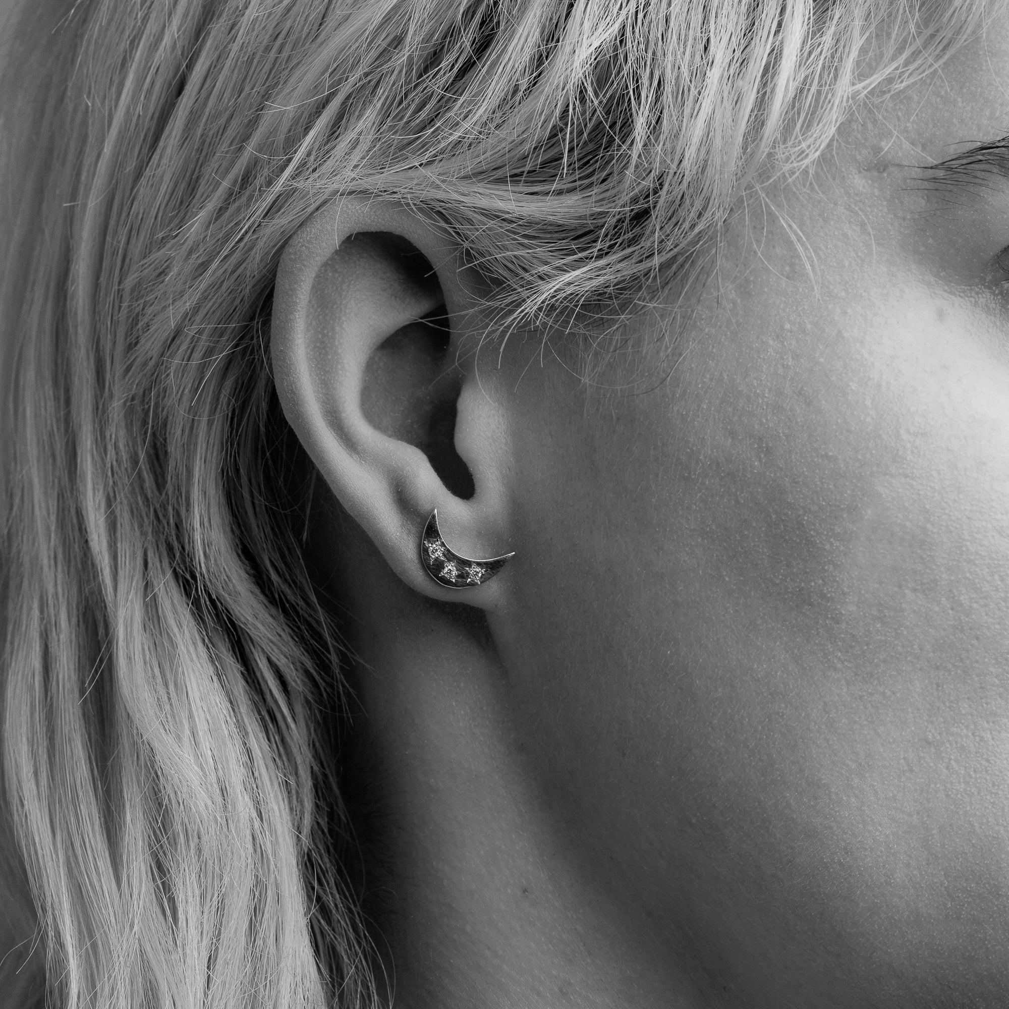 Handmade 9 carat yellow gold moon shaped studs, set with four round diamonds, worn on a model.