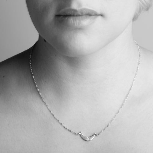 Crescent moon shaped pendant with diamond set in centre. Bespoke, handmade in Melbourne by Black Finch Jewellery. Shown on model.