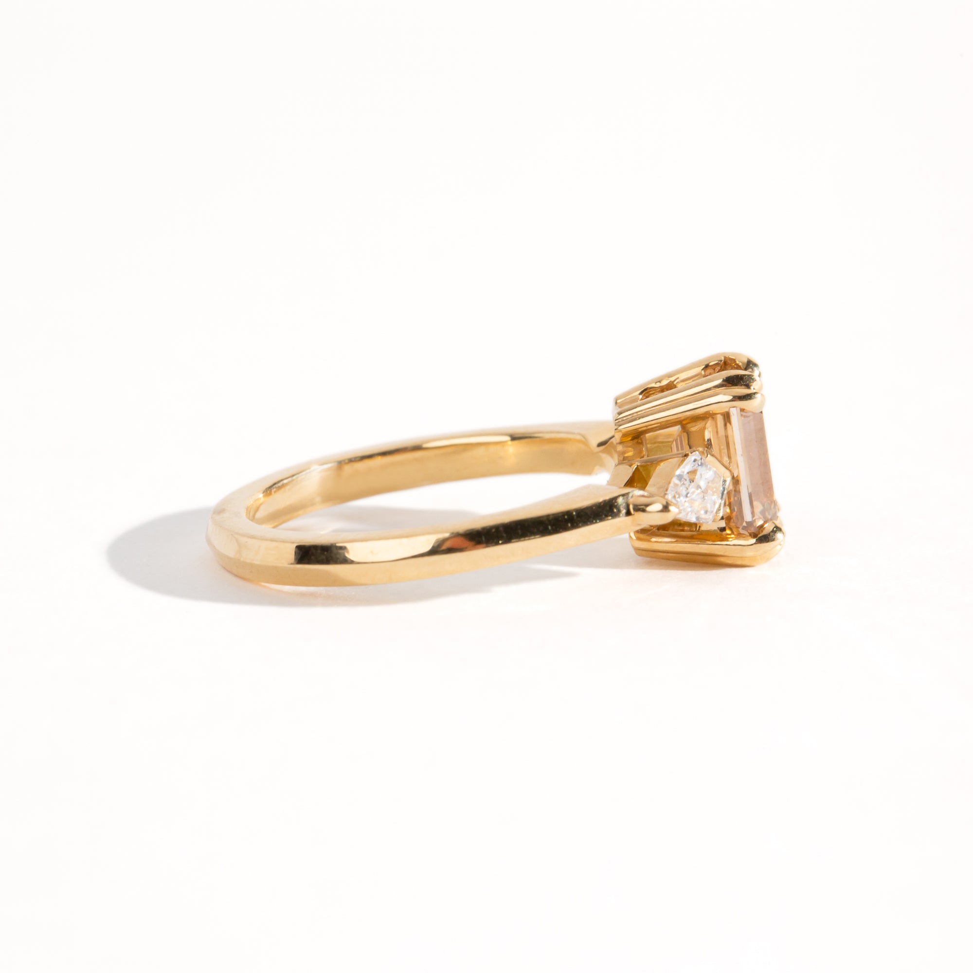 Bespoke engagement ring with rectangular radiant cut champagne diamond surrounded by kite cut white diamonds. Recycled, refined gold custom and crafted in Melbourne by black Finch Jewellery