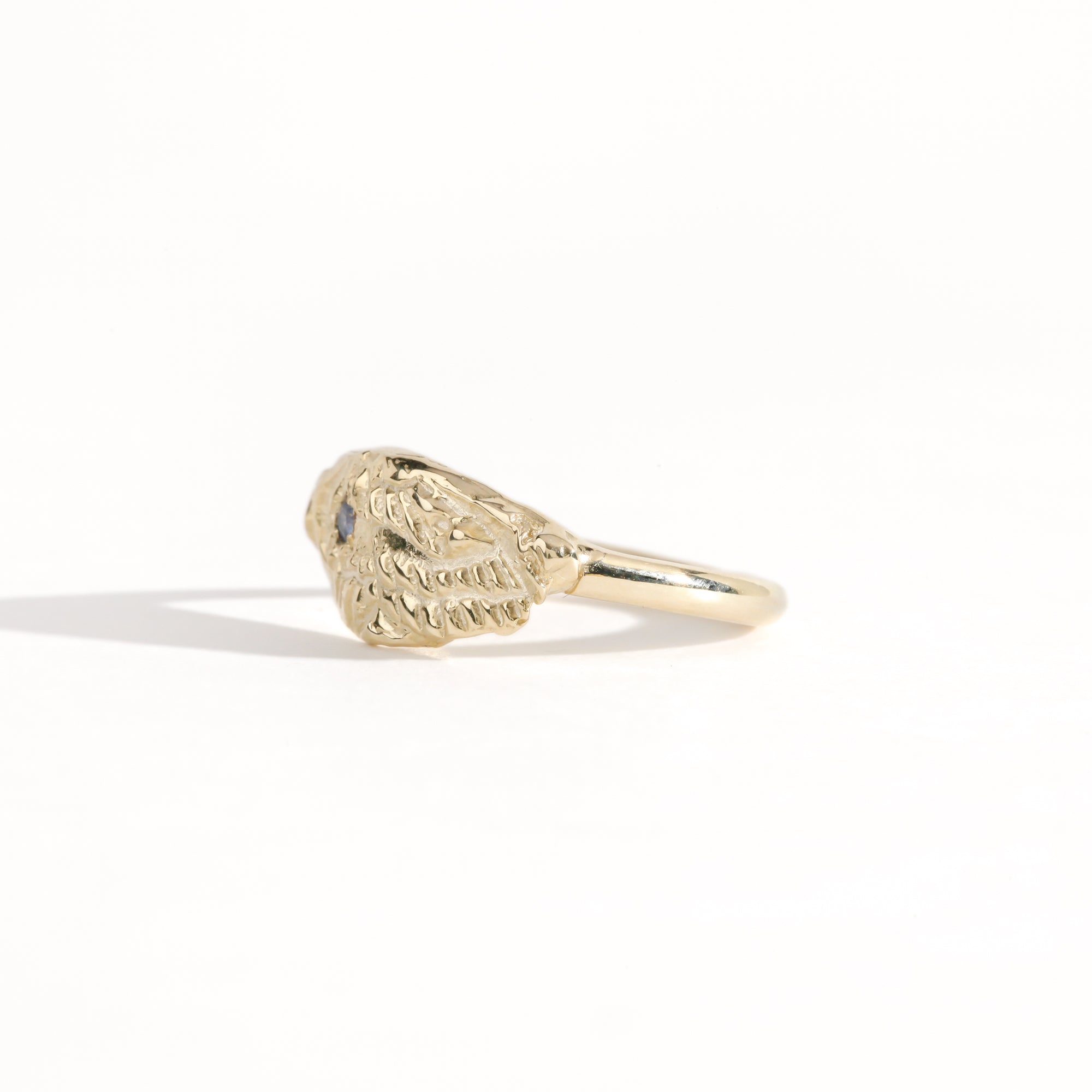 Gold ring featuring wing detailing and blue sapphire. Handmade and bespoke finish.