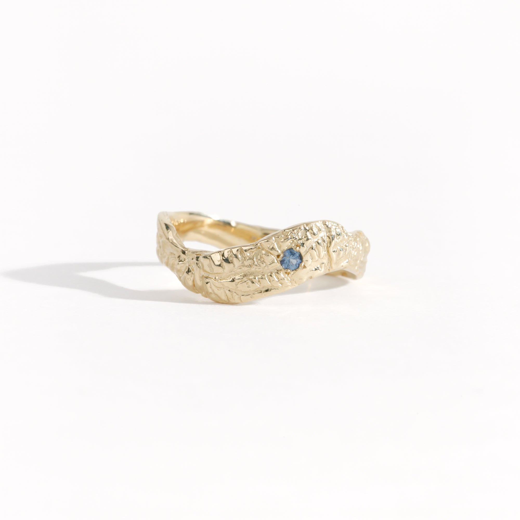 Gold ring featuring wing detailing and blue sapphire. Handmade and bespoke finish.