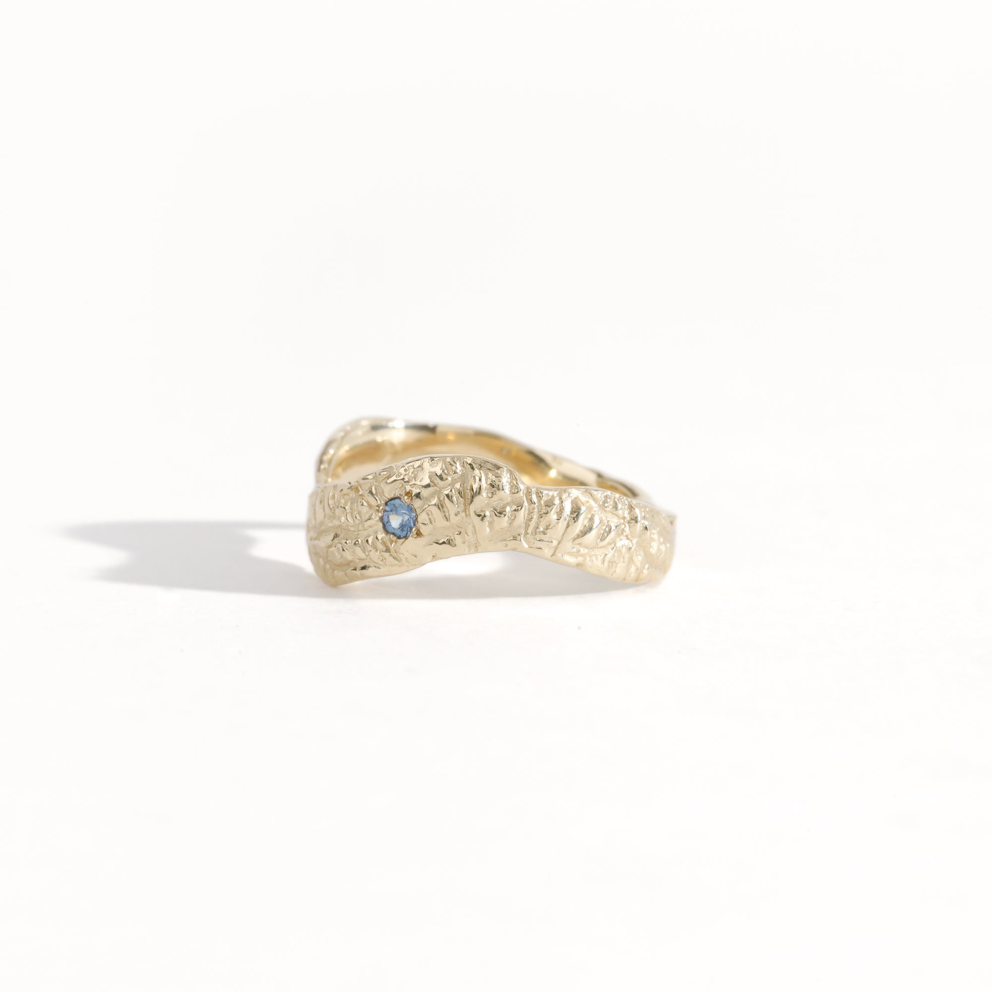 Gold ring featuring wing detailing and blue sapphire. Handmade and bespoke finish.