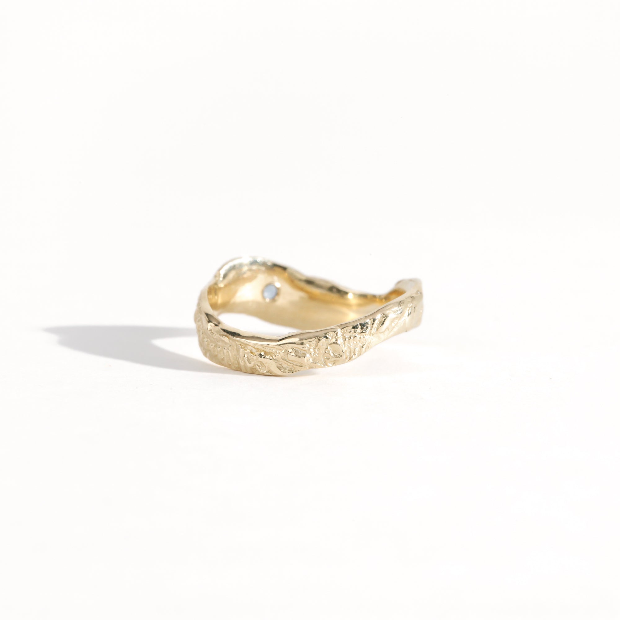 Gold ring featuring wing detailing and blue sapphire. Handmade and bespoke finish.
