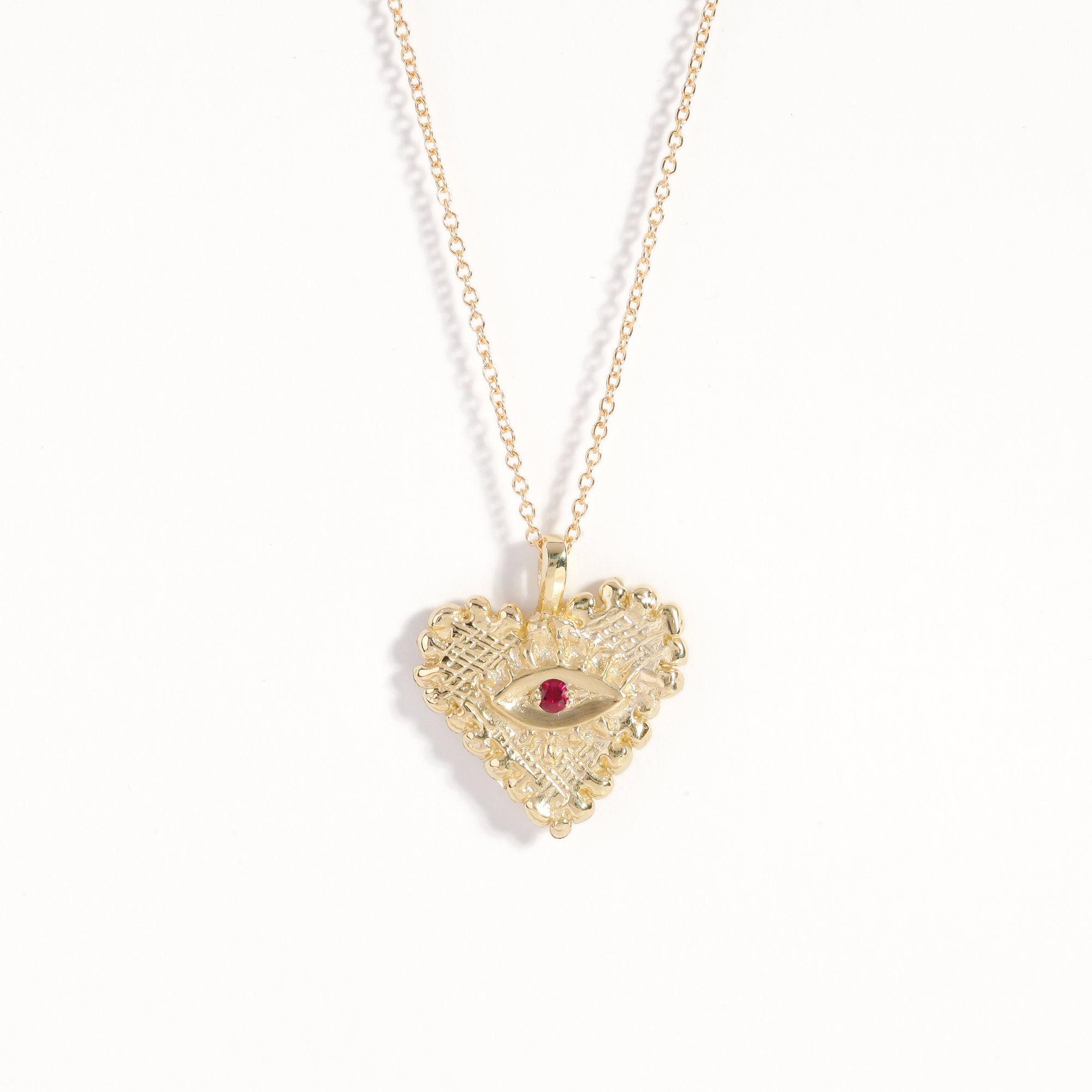 Handmade 9 carat yellow gold heart pendant set with a ruby in centre of eye detail on 9 carat yellow gold chain.