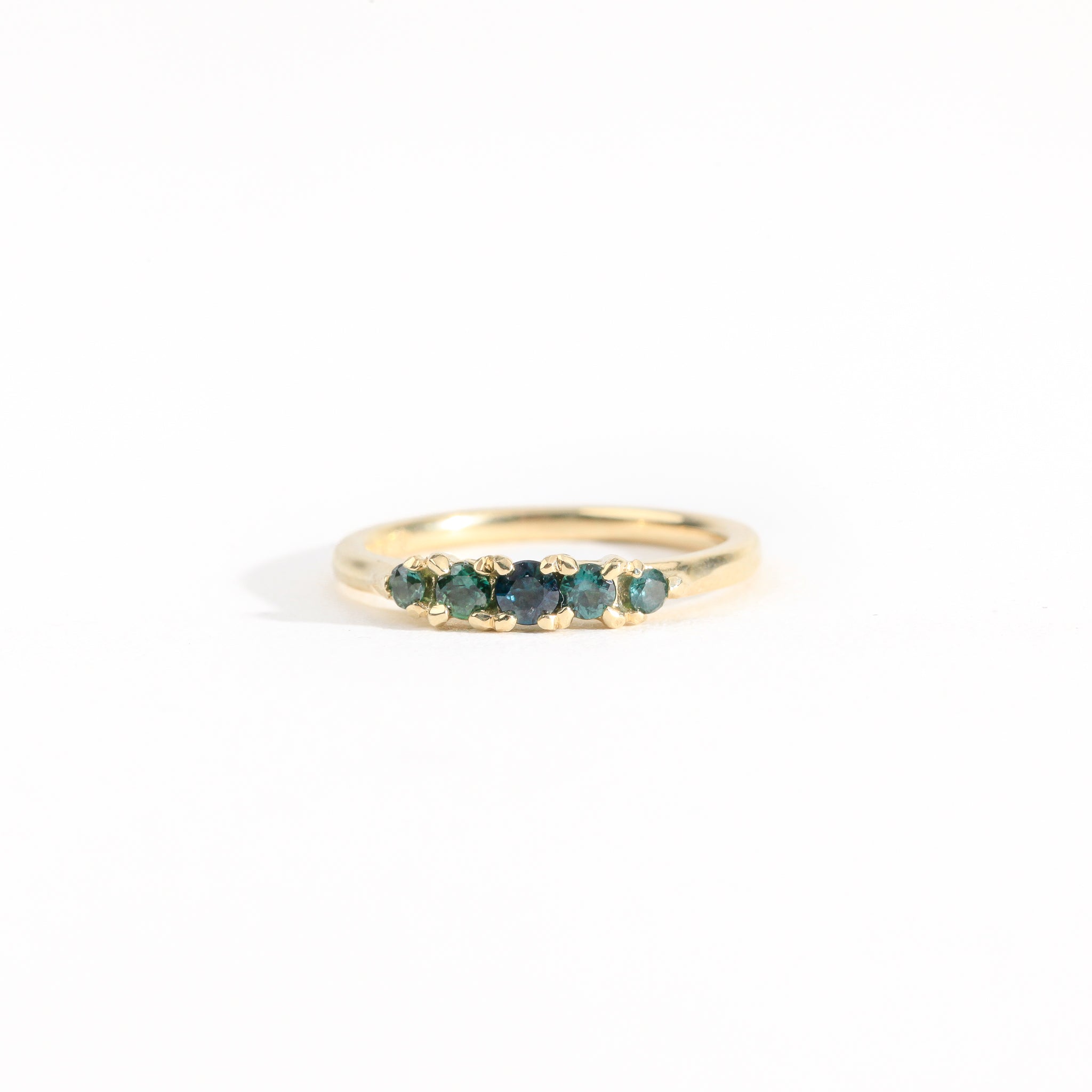 A bespoke handcrafted five stone ring in yellow gold with ethically sourced Australian teal sapphires