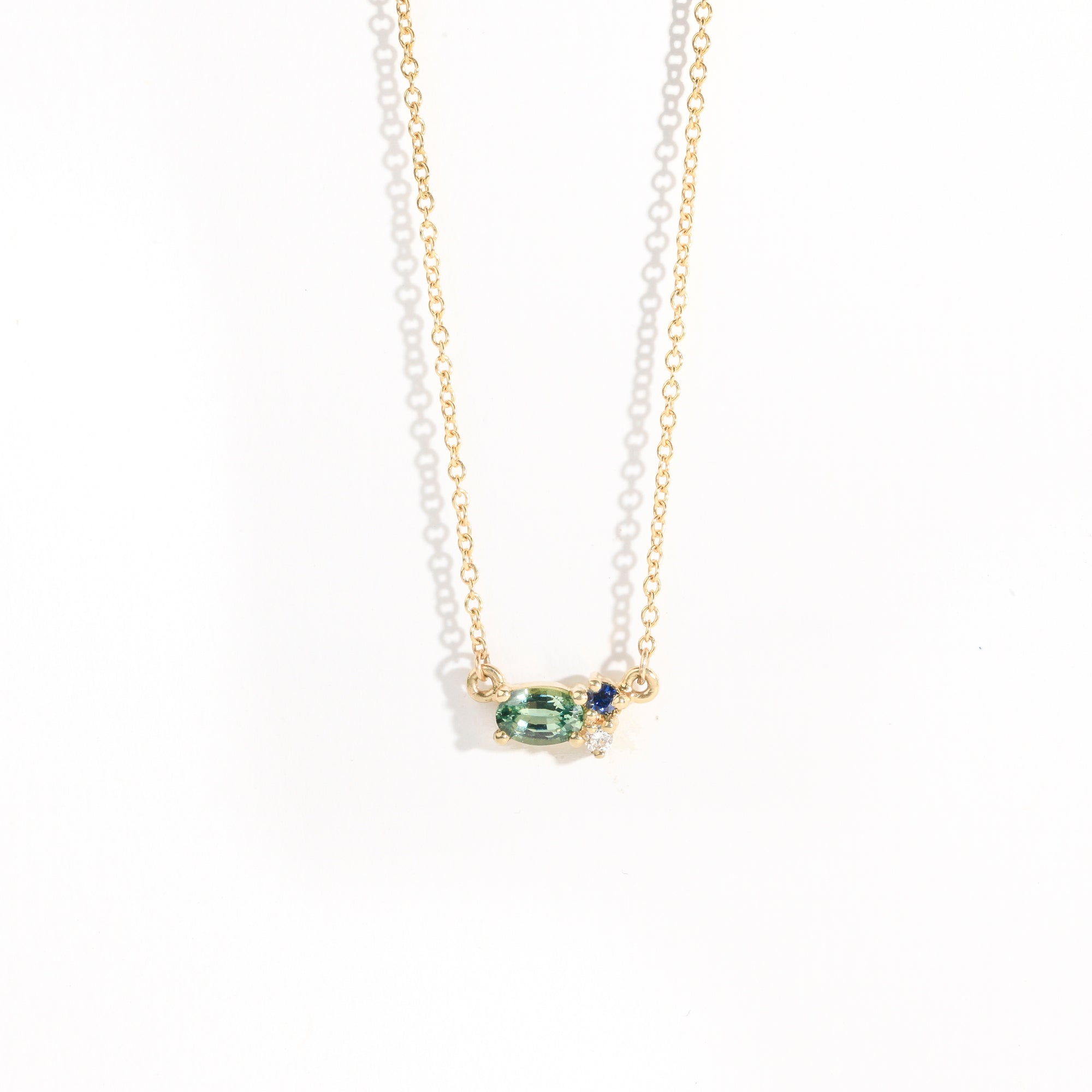 9 carat yellow gold three stone pendant, with a central green ethically sourced Australian sapphire, a deep blue round sapphire and a white diamond. 
