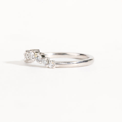 18 carat white gold woman's wedding band with 7 round white diamonds, claw set in a slight curve.