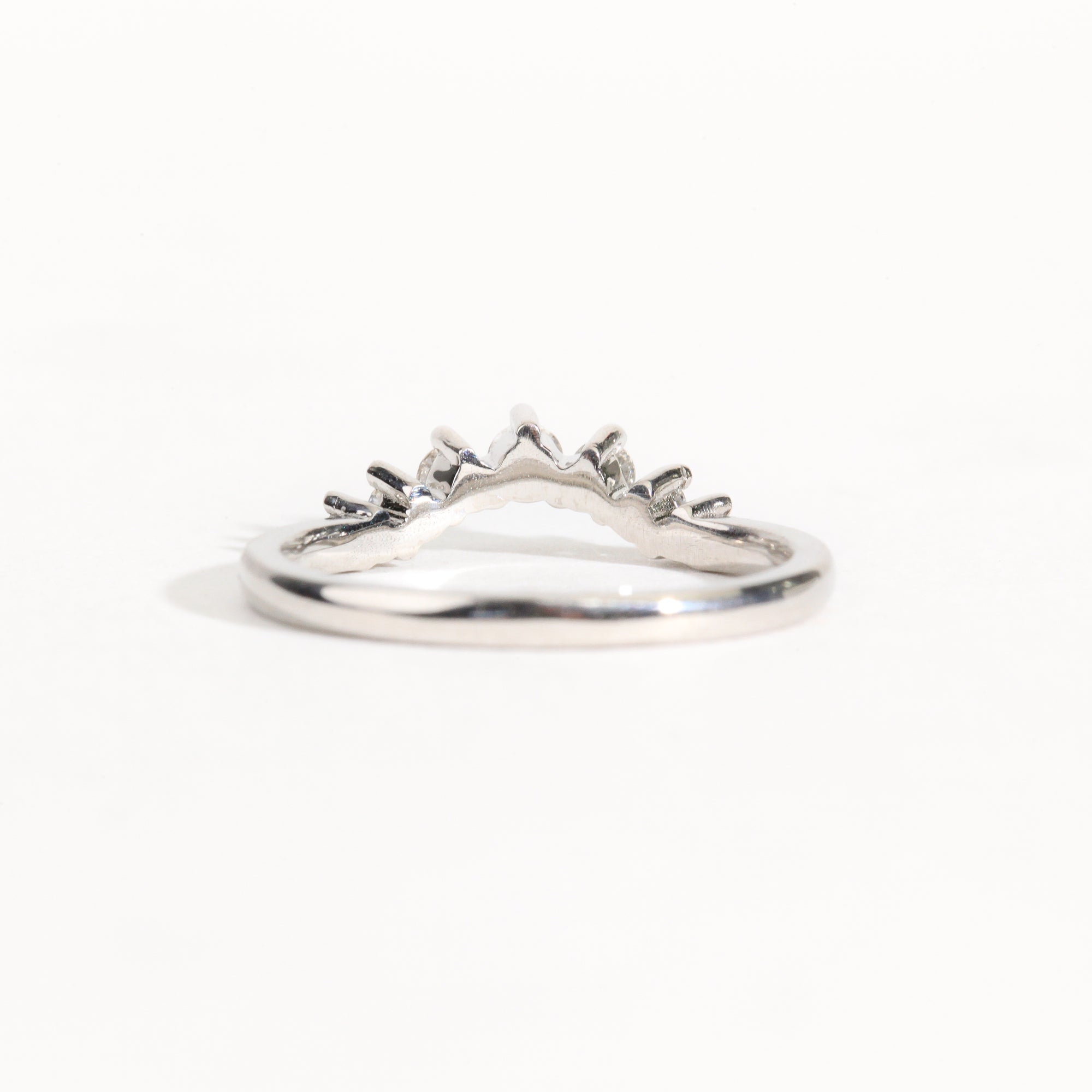 18 carat white gold woman's wedding band with 7 round white diamonds, claw set in a slight curve.