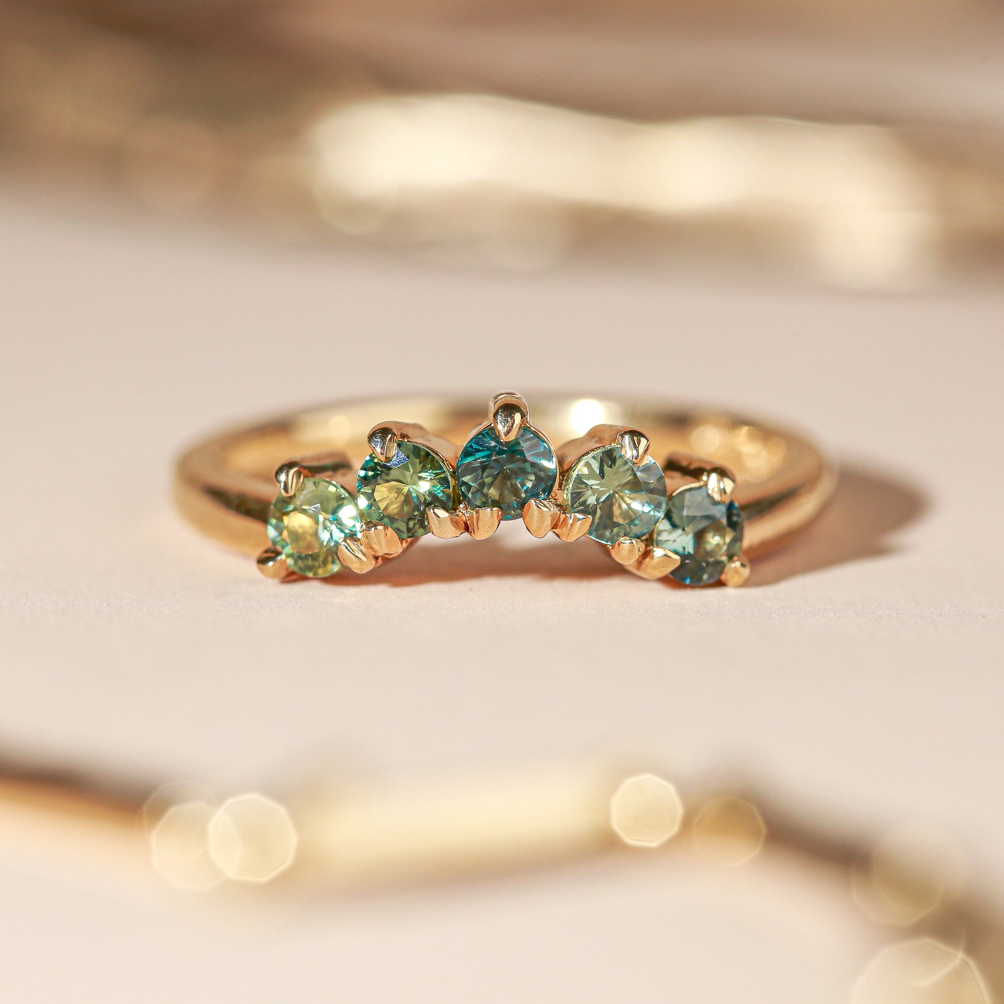 18 carat yellow gold woman's wedding band with 5 round, ethically sourced Australian blue/green parti sapphires, claw set in a slight curve.