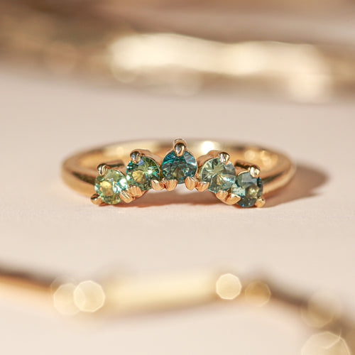 18 carat yellow gold woman's wedding band with 5 round, ethically sourced Australian blue/green parti sapphires, claw set in a slight curve.