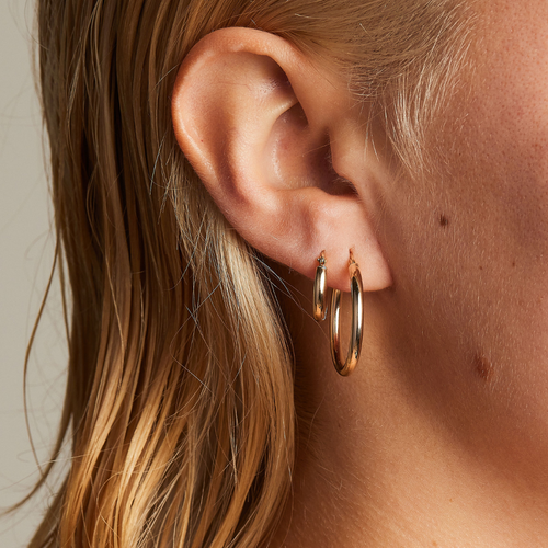 Classic 9 carat gold hoop earrings, worn with the classic small 9 carat gold hoops on a model. 