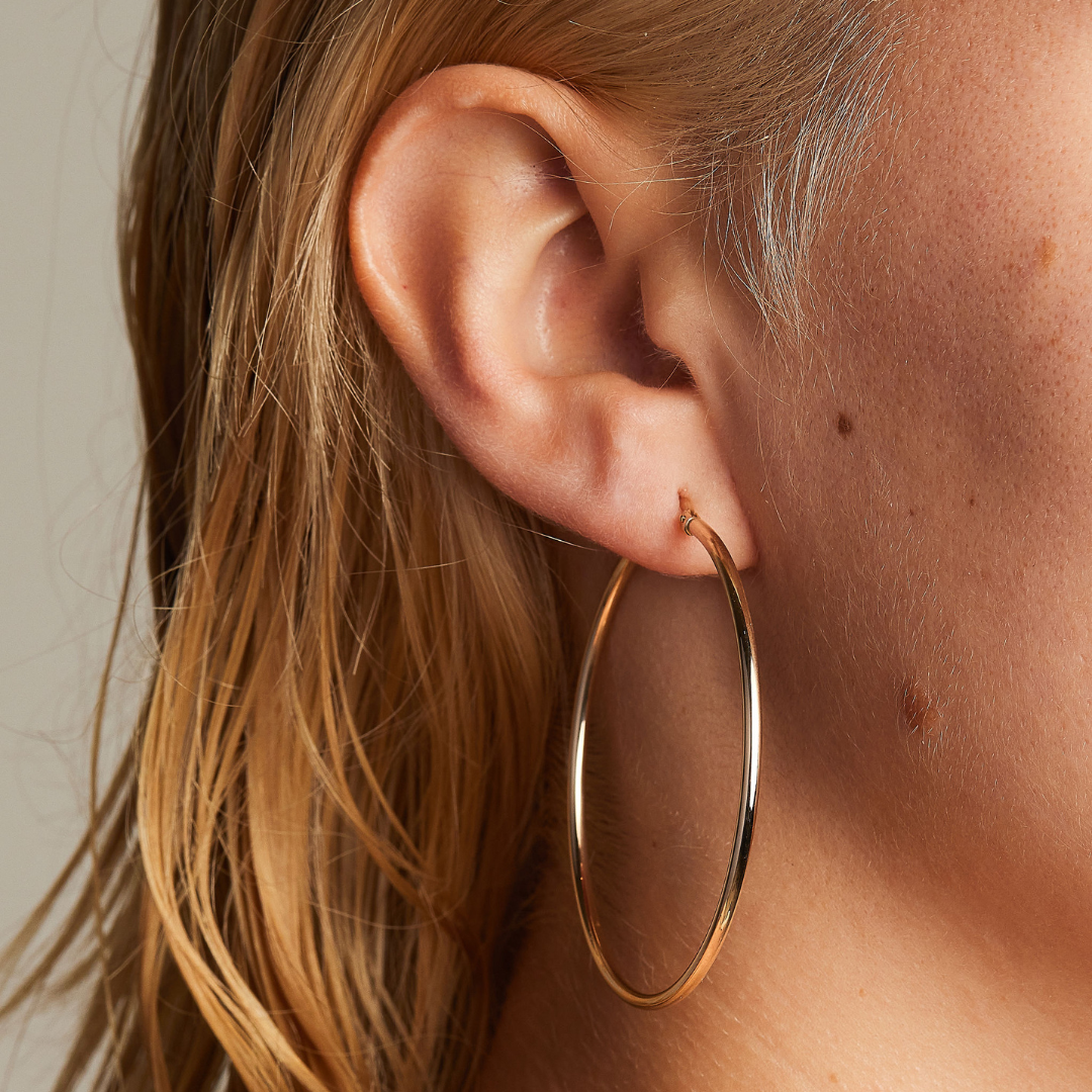 Classic 9 carat yellow gold hoops, worn on a model.
