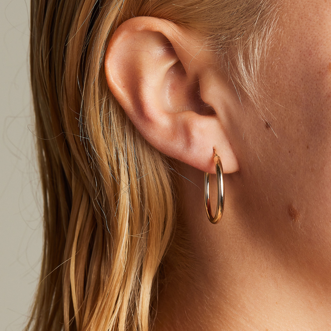 Classic 9 carat gold hoop earrings, worn on a model. 