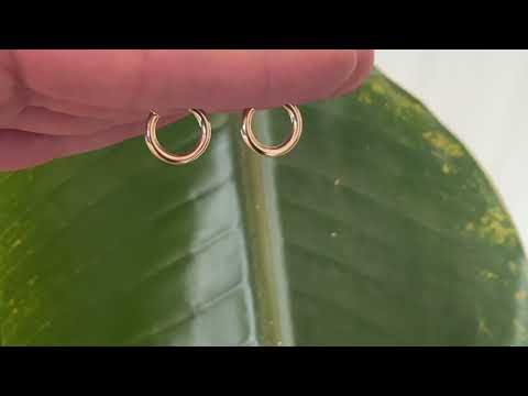 Classic 9 carat yellow gold hoops, displayed on the hand, gently catching the sunlight. 