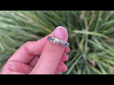 Handmade wedding band in 18 carat white gold, with nine blue and teal ethically sourced Australian sapphires, worn on the hand.