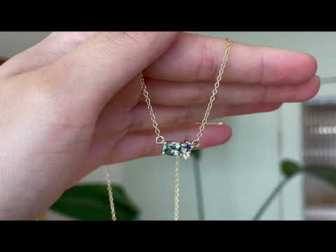 9 carat yellow gold three stone pendant, with a central green ethically sourced Australian sapphire, a deep blue round sapphire and a white diamond, hanging gently, catching the sunlight. 